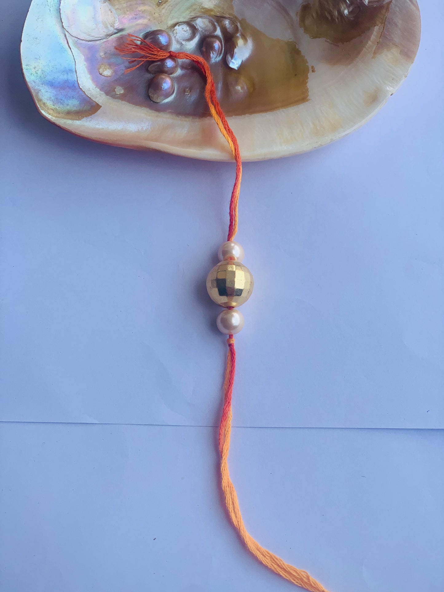 Golden ball with pearl mauli rakhi